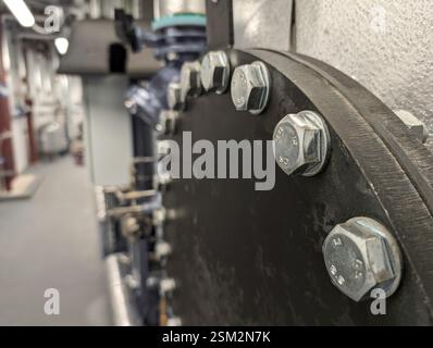 Una grande flangia per tubi industriali con più bulloni esagonali che la fissano. Bulloni in acciaio zincato , che garantiscono durata e resistenza alla corrosione. Foto Stock