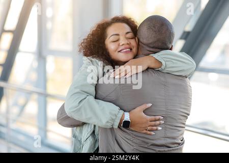 Bentornato. Donna africana felice che abbraccia il suo fidanzato amorevole, spazio libero Foto Stock