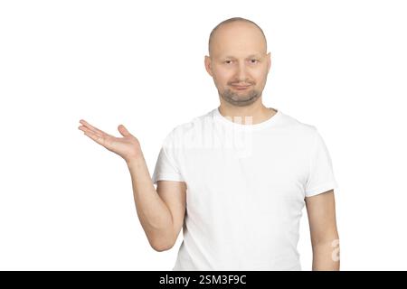 Un uomo caucasico calvo con stoppie leggere e una t-shirt bianca si staglia su uno sfondo semplice. Foto Stock