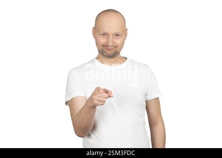 Un uomo caucasico calvo con una barba corta indossa una t-shirt bianca e punta con sicurezza direttamente alla fotocamera. Foto Stock