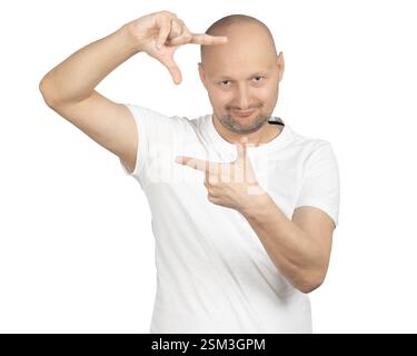 Un uomo calvo con una t-shirt bianca sta facendo un gesto rettangolare con le mani sorridendo scherzosamente. Foto Stock