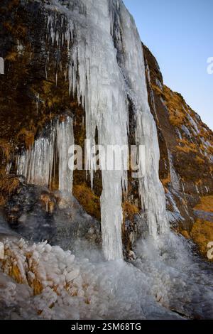 Una cascata ghiacciata mozzafiato in Islanda, circondata da scogliere ghiacciate e paesaggi innevati, catturando la bellezza selvaggia dell'inverno. Foto Stock