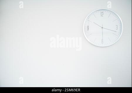 bianco 24 ore su 24 su un muro bianco. l'orologio si trova nella parte superiore destra Foto Stock