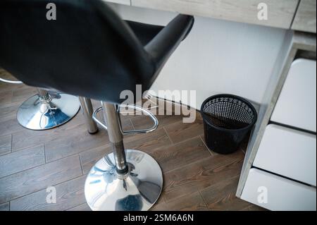 cestino in ufficio. accanto c'è una sedia su un'alta base in acciaio. Foto Stock