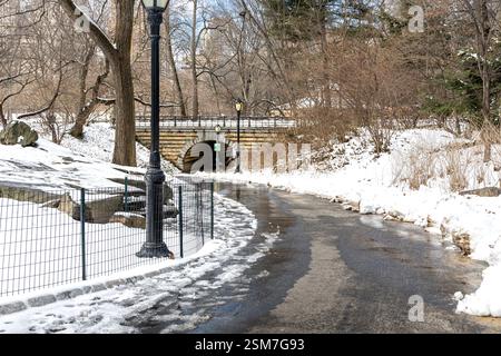 Una splendida giornata invernale a Central Park, caratterizzata da un percorso verso un arco di ponte circondato dalla neve il 10 febbraio 2025 a Manhattan. Foto Stock