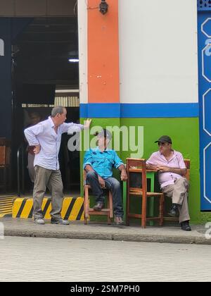 Tre uomini sedevano su sedie fuori da un negozio a Jardin, Antioquia, Colombia Foto Stock