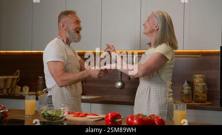 Romantico anziano in pensione famiglia caucasica coppia ballare valzer celebrare anniversario matrimonio cucina cena vecchio marito spin moglie di mezza età in ballo Foto Stock