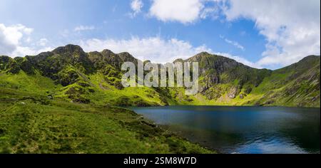 Pendii verdi vividi e picchi scoscesi di Penygader (Cadair Idris) che riflettono la bellezza Rugged di Llyn Cau nel Parco Nazionale di Snowdonia Foto Stock