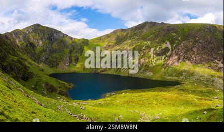 Pendii verdi vividi e picchi scoscesi di Penygader (Cadair Idris) che riflettono la bellezza Rugged di Llyn Cau nel Parco Nazionale di Snowdonia Foto Stock