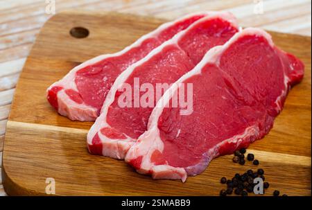 primo piano di pezzi di manzo marmorizzato su tavola di legno Foto Stock