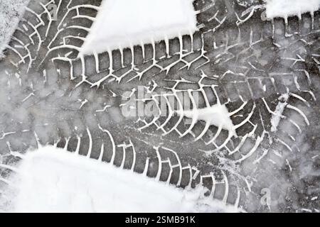 Tracce di pneumatici su sfondo bianco neve fresca sull'asfalto Foto Stock