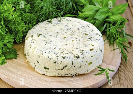 In casa formaggio rotondo con erbe e spezie su una tavola di legno Foto Stock