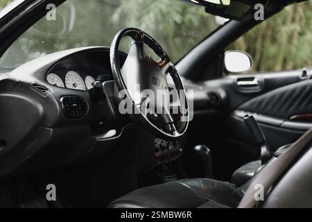 Primo piano del volante e del cruscotto di un'auto con sedili in pelle visibili Foto Stock