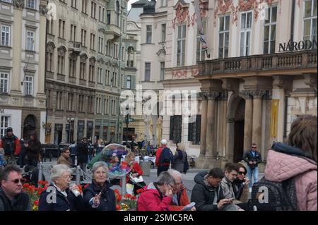Una vivace strada centrale di Praga è piena di gente che va avanti la propria giornata. L'architettura storica degli edifici che costeggiano la strada crea Foto Stock