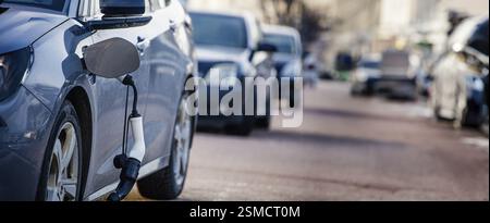Diverse auto allineate su una strada della città con una sola ricarica per auto elettriche Foto Stock