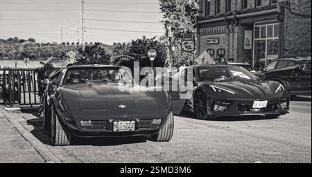 Port Perry, Ontario, Canada - 2024 10 05: Rosso vintage 1974 Chevrolet Corvette Stingray coupé e rosso moderno 2020 Chevrolet Corvette C8 su Queen Street Foto Stock