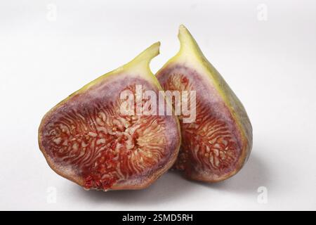 Frutta, un fico Ficus carica Anjir tagliato in due pezzi su sfondo bianco Foto Stock