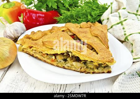Torta con cavolo, sorrel e peperoni in una piastra bianca, igienico, prezzemolo sullo sfondo la luce di tavole di legno Foto Stock