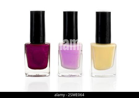 Tre flaconi con smalto per unghie giallo, viola e rosa isolati su sfondo bianco Foto Stock