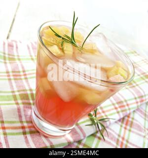La limonata con il rabarbaro e il rosmarino in un bicchiere su un tovagliolo su tavole di legno sfondo Foto Stock