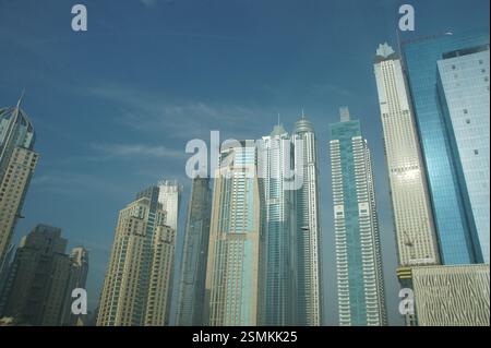 Un gruppo di grattacieli perforano un cielo blu luminoso a Dubai, una testimonianza dell'ambizione umana e della costante spinta verso nuove altezze. Foto Stock