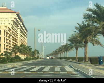 Sfondo dell'hotel Dubai, sulla strada alberata di palme. Tranquilla fuga dalla frenetica città. Un mix perfetto di tranquillità urbana. Foto Stock