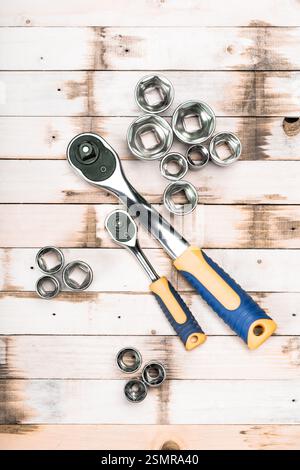 Collezione di chiavi a cricchetto e bussole su superfici in legno che presentano utensili utilizzati per attività meccaniche Foto Stock