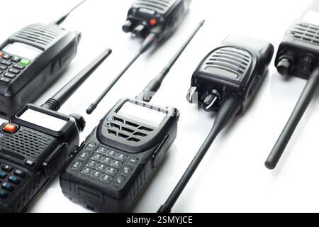 Vari modelli di walkie talkie disposti su una superficie bianca per la presentazione della tecnologia nei dispositivi di comunicazione Foto Stock