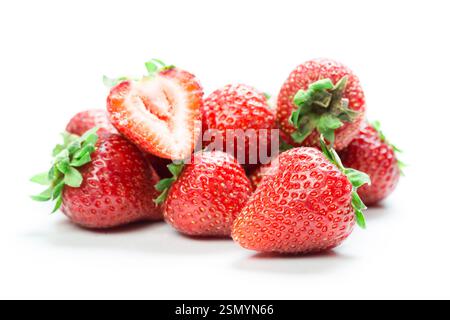 Fragole fresche disposte su una superficie bianca con una tagliata a metà per rivelare una polpa rossa succosa Foto Stock