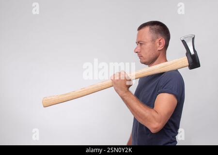 un uomo con un'ascia su sfondo grigio. vista laterale Foto Stock