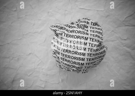 Palla di carta schiacciata con parole terrorismo su sfondo strappato di carta bianca. Foto Stock