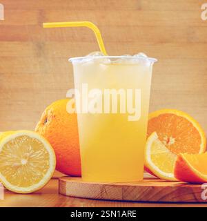 Bevanda rinfrescante agli agrumi con fette di arancia e limone servita su una tavola di legno durante il pomeriggio estivo Foto Stock