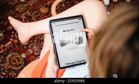 Parigi, Francia - 11 giugno 2023: Una donna siede comodamente, sfogliando un articolo su Apple Vision Pro su un tablet - lo schermo visualizza un'immagine promozionale o Foto Stock