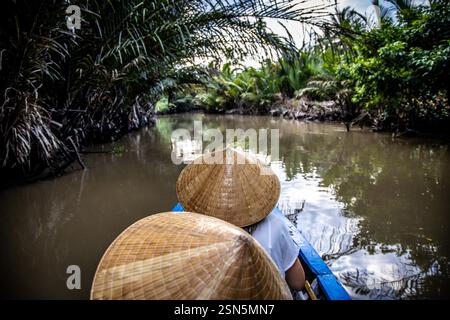 Prosciutto Luong - Vietnam 18 agosto 2024 - barca che viaggia lungo un braccio laterale del fiume Ham Luong nel Delta del Mekong del Vietnam, attraverso un paesaggio unico dom Foto Stock