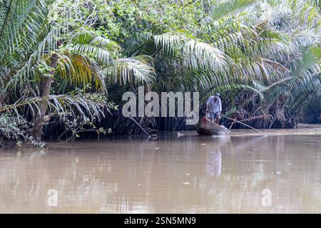 Prosciutto Luong - Vietnam 18 agosto 2024 - barca che viaggia lungo un braccio laterale del fiume Ham Luong nel Delta del Mekong del Vietnam, attraverso un paesaggio unico dom Foto Stock