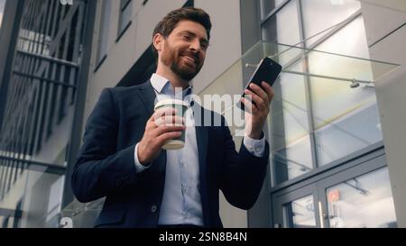 Felice successo sorridente adulto di mezza età uomo caucasico ragazzo maschio imprenditore imprenditore imprenditore che cammina in un edificio di uffici della città Foto Stock