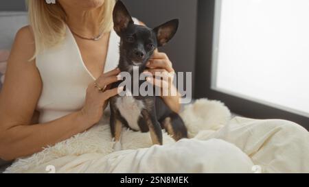 Donna che tiene un cane chihuahua in salotto mostrando affetto Foto Stock