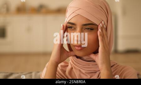 Ritratto triste pensiero frustrato malato malato cattivo stress donna indiana ragazza araba donna musulmana donna islamica in hijab a casa tenere testa dolorosa Foto Stock