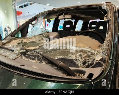Leopoli, Ucraina - 12 febbraio 2025: Auto militare gravemente danneggiata con parabrezza in vetro frantumato in un ambiente commerciale Foto Stock