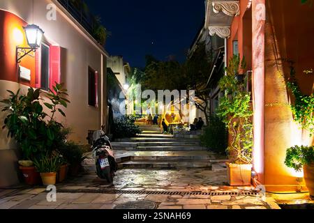 Un caffè e ristorante sul marciapiede in un vicolo colorato di notte nello storico quartiere Plaka sotto l'acropoli ad Atene in Grecia. Foto Stock