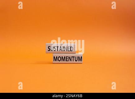 Simbolo di slancio prolungato. Blocchi di legno con le parole ritmo sostenuto. Bellissimo sfondo arancione. Concetto di business e di slancio costante. Servizio fotocopie Foto Stock