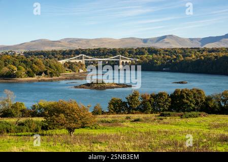 Il famoso ponte sospeso Menai da un punto panoramico ben noto di Anglesey con le montagne della terraferma gallese sullo sfondo. Foto Stock