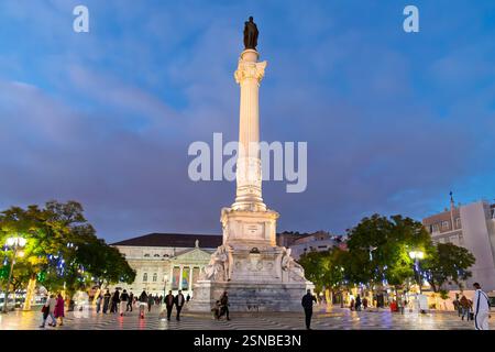 Una colonna illuminata del monumento di Pietro IV all'ora blu crepuscolo in prima serata in Piazza Rossio nel quartiere Baixa di Lisbona, Portogallo. Foto Stock