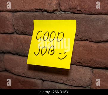 La nota gialla brillante incoraggia la positività sulla parete in mattoni Foto Stock