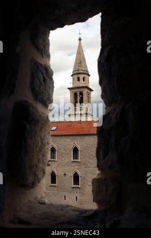 La Chiesa di San Giovanni Battista, vista attraverso una fessura nel muro della fortezza, Budva, Montenegro Foto Stock