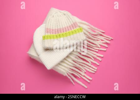 Caldi cappelli di lana e sciarpa su sfondo rosa, sopra la vista Foto Stock