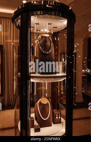 Eleganti perle bianche e moderni gioielli metallici, collana e orecchini sulla vetrina del negozio di accessori donna Foto Stock