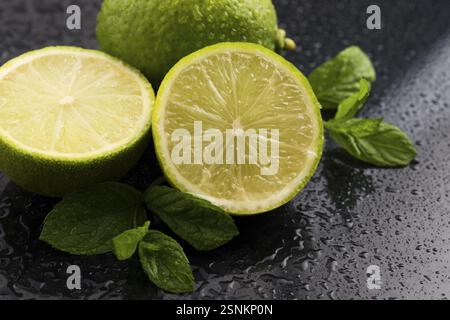 Verde lime con la menta e gocce di acqua su sfondo nero Foto Stock
