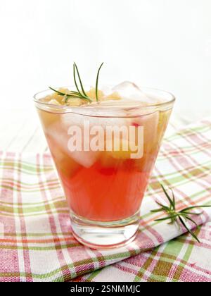 La limonata con il rabarbaro e il rosmarino in un bicchiere su un tovagliolo a scacchi su tavole di legno sfondo Foto Stock