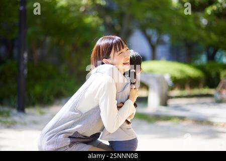 Donna sorridente che abbraccia un bambino Foto Stock